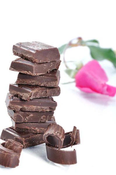 Schokolade, Tisch, Stücke und Rose auf weißem Hintergrund — Stockfoto
