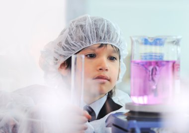 Akıllı şirin küçük erkek çocuk çok modern hastane laboratuarında test tüpleri ile deneyler
