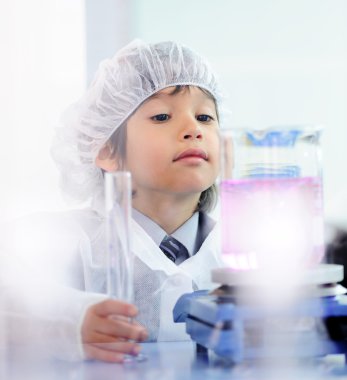 Akıllı şirin küçük erkek çocuk çok modern hastane laboratuarında test tüpleri ile deneyler