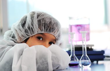 Akıllı şirin küçük erkek çocuk çok modern hastane laboratuarında test tüpleri ile deneyler