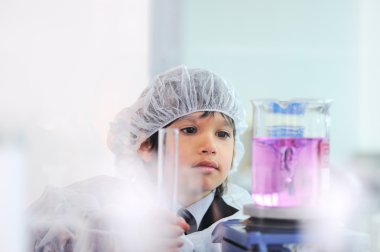 Akıllı şirin küçük erkek çocuk çok modern hastane laboratuarında test tüpleri ile deneyler