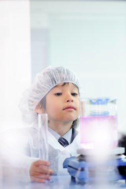 Akıllı şirin küçük erkek çocuk çok modern hastane laboratuarında test tüpleri ile deneyler