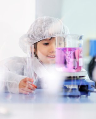 Akıllı şirin küçük erkek çocuk çok modern hastane laboratuarında test tüpleri ile deneyler