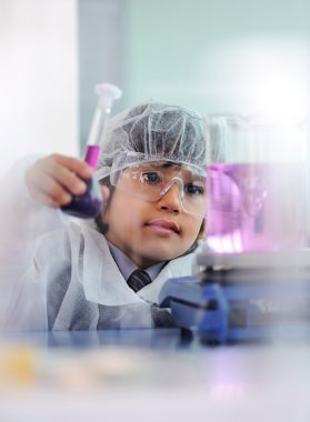Akıllı şirin küçük erkek çocuk çok modern hastane laboratuarında test tüpleri ile deneyler