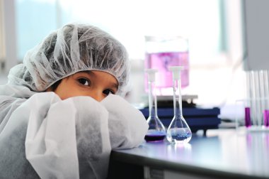 Akıllı şirin küçük erkek çocuk çok modern hastane laboratuarında test tüpleri ile deneyler