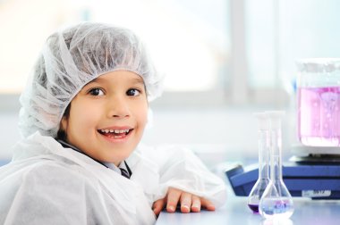 Akıllı şirin küçük erkek çocuk çok modern hastane laboratuarında test tüpleri ile deneyler