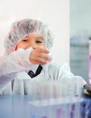 Akıllı şirin küçük erkek çocuk çok modern hastane laboratuarında test tüpleri ile deneyler