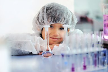 Akıllı şirin küçük erkek çocuk çok modern hastane laboratuarında test tüpleri ile deneyler
