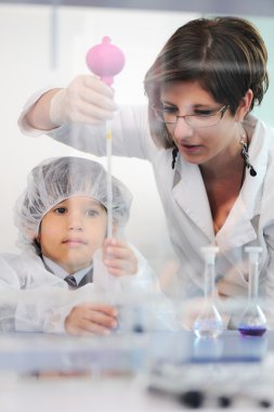 Akıllı şirin küçük erkek çocuk onun anne doktor bilim adamı ile laboratuarda deney