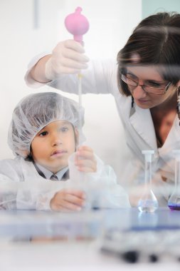 Akıllı şirin küçük erkek çocuk onun anne doktor bilim adamı ile laboratuarda deney