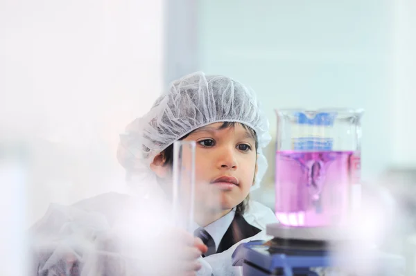Niño masculino lindo inteligente que experimenta con tubos de ensayo en el laboratorio hospitalario moderno real — Foto de Stock