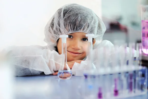 Inteligente bonito pequeno macho criança experimentando com tubos de ensaio no real moderno laboratório hospitalar — Fotografia de Stock