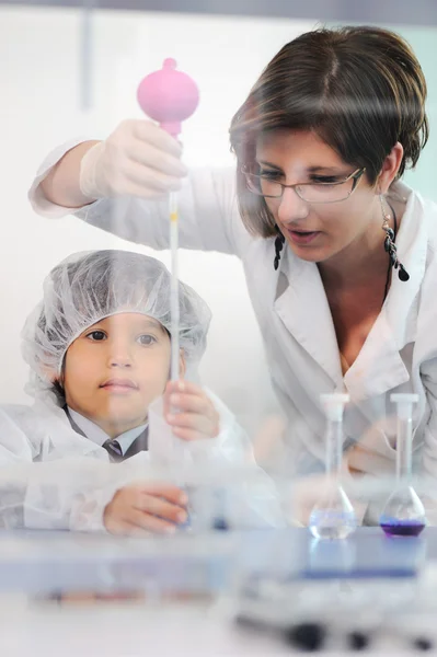 Inteligente bonito pequeno macho criança experimentando em laboratório com sua mãe médico cientista — Fotografia de Stock