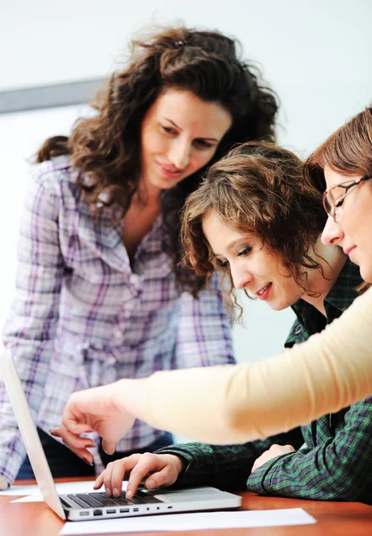 Groupe de jeunes heureux à la recherche d'un ordinateur portable travaillant dessus — Photo