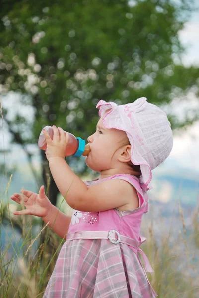 Adorable little girl drinking from bottle outdoor — Stock Photo, Image