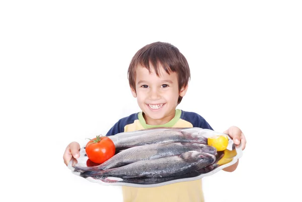 Niño sonriente con pescado fresco en la mesa — Foto de Stock