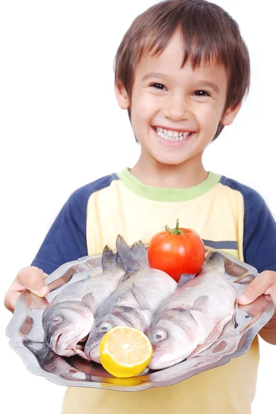 Uśmiechnięte dziecko z trzech świeżych ryb na stole — Zdjęcie stockowe