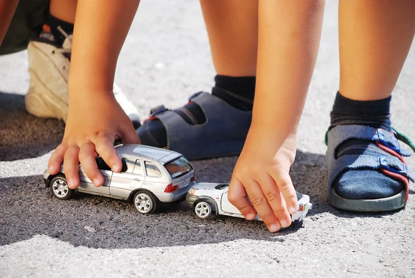 Toys cars in front of children legs — Stock Photo, Image