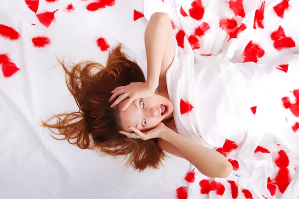 Красивая девушка лежала на кровати с белыми простынями крича — стоковое фото