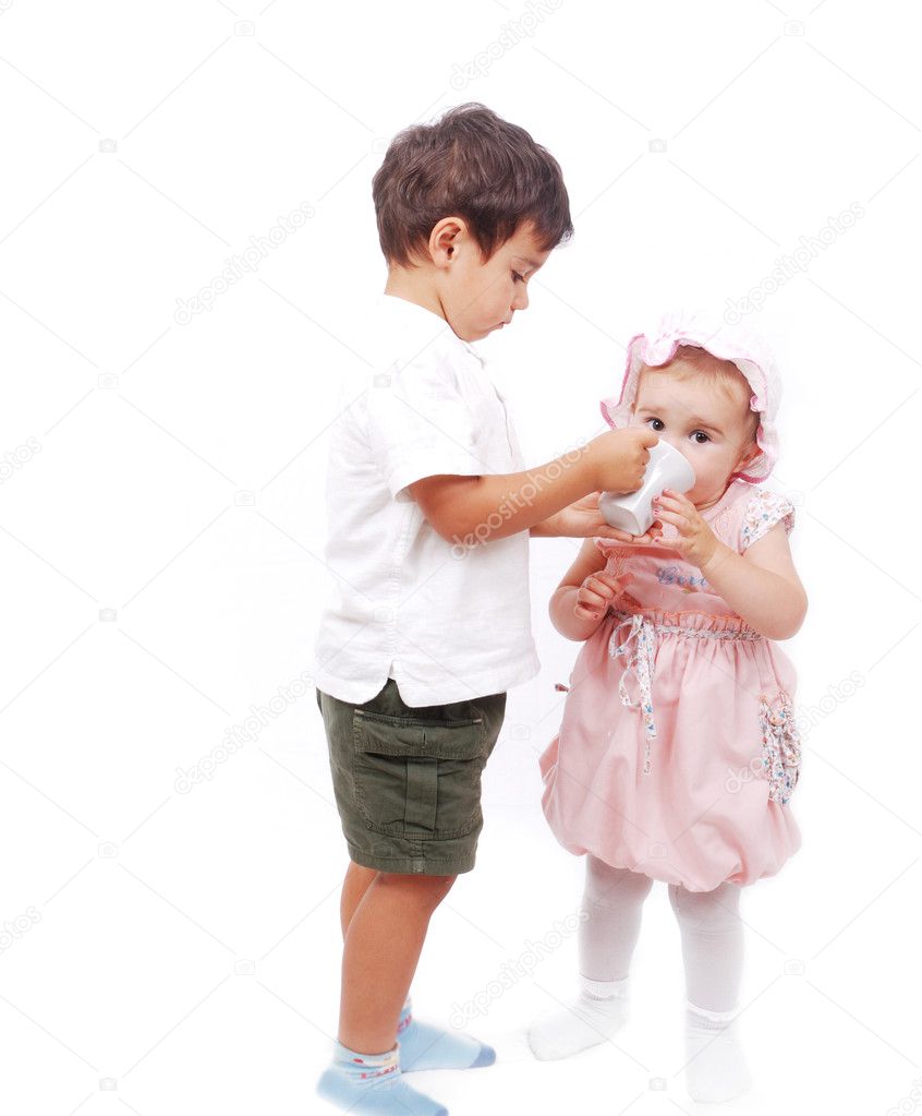 A little kid is feeding his sister