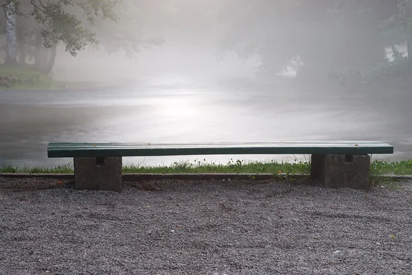Una panchina a parte il fiume al mattino — Foto Stock