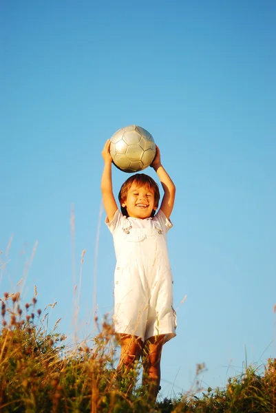 Pequeño niño lindo con bola por encima de la cabeza en lugar adorable al aire libre —  Fotos de Stock