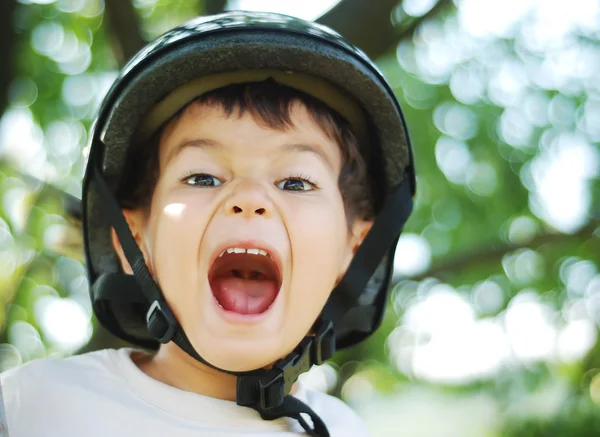 Kleines sehr nettes Kind mit Helm auf dem Kopf und lustigem geöffnetem Mund — Stockfoto