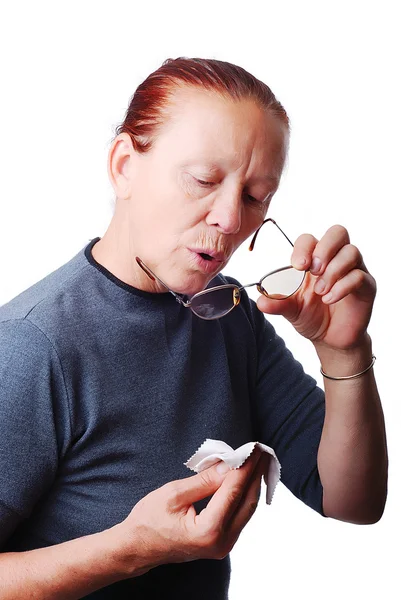 Idős nő tisztítására a szemüvegét Stock Kép