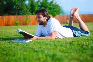 genç adam yeşil yerde yatan ve öğrenme