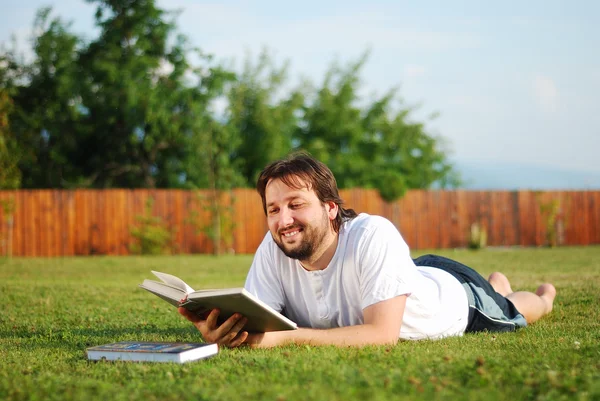 Le jeune homme est allongé sur un terrain vert et apprend — Photo