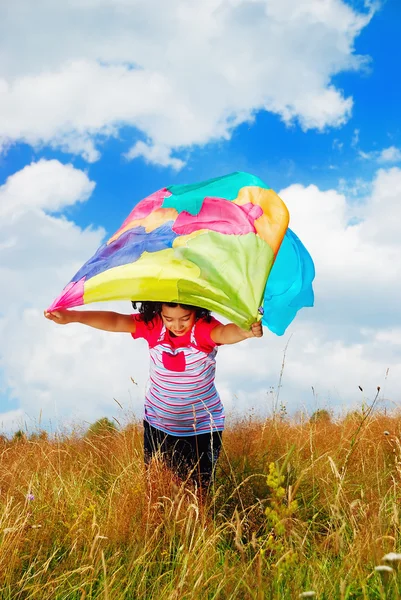 Маленькая симпатичная девочка с шарфом над головой на медоу — стоковое фото