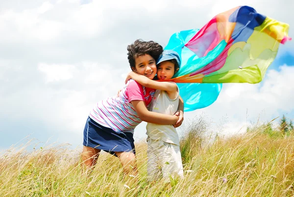 Маленькая симпатичная девочка и мальчик с шарфом над головой на медоу — стоковое фото
