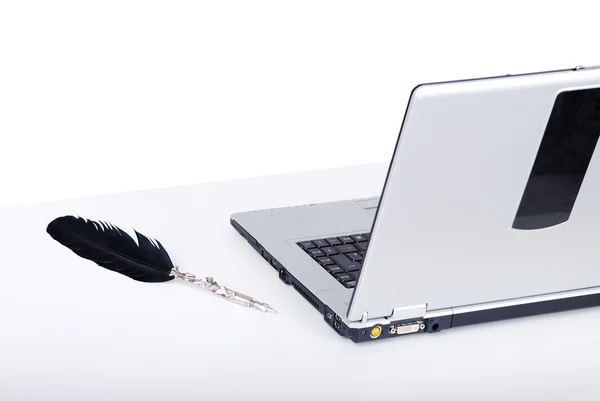 Peří a laptop na stole bílý — Stock fotografie
