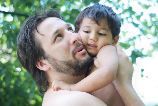 Chico encantador y su padre tomándolo en las manos en la naturaleza —  Fotos de Stock