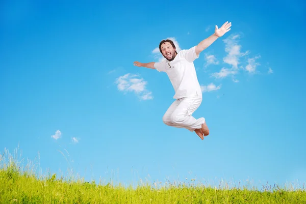 Happy young mane in white jumping on beautiful meadow — Stock Photo, Image