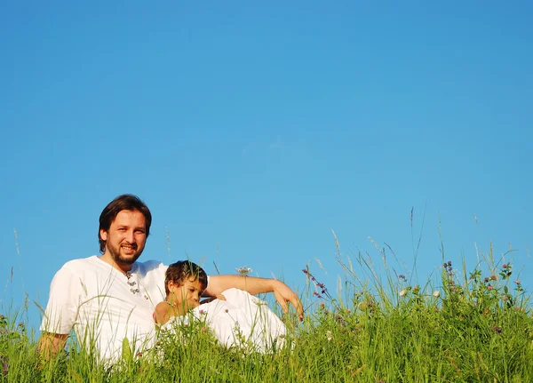 Padre joven en blanco con niño en el hermoso prado —  Fotos de Stock