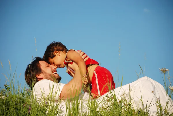 Padre joven en blanco con niño en el hermoso prado —  Fotos de Stock