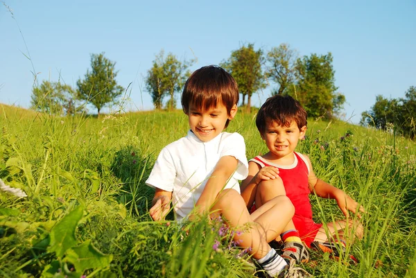 Pequenas crianças bonitos no belo campo verde — Fotografia de Stock