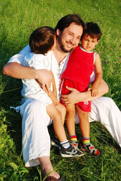 Padre joven en blanco con niños en el hermoso prado —  Fotos de Stock