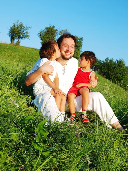 Young father in white with children on beautiful meadow — Stock Photo, Image