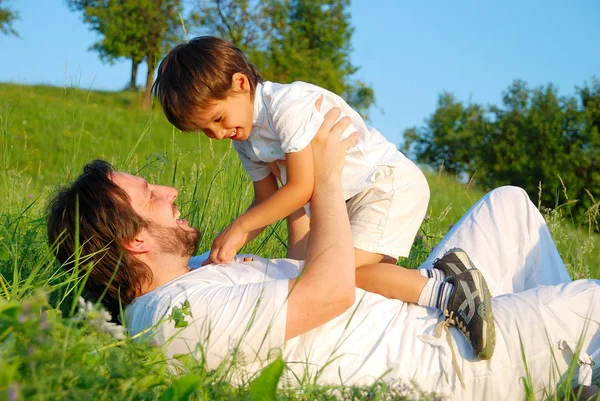 Padre joven en blanco con niño en el hermoso prado — Foto de Stock