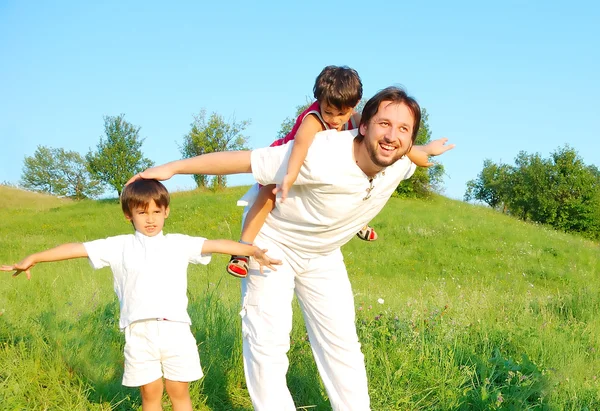 Padre joven en blanco con niños en el hermoso prado — Foto de Stock