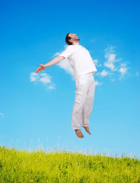 Happy young mane in white jumping on beautiful meadow — Stock Photo, Image