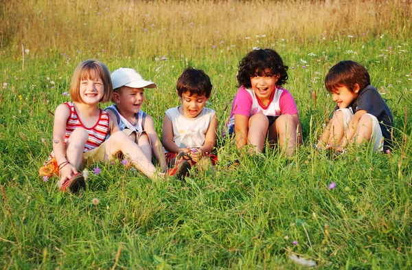 Happy little children in grass on meadow — Stock Photo, Image