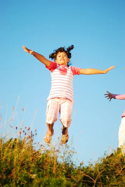 Glad liten flicka hoppande och joying i naturen — Stockfoto