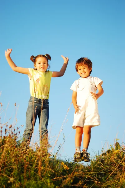 Menina e criança feliz pulando e gozando na natureza — Fotografia de Stock