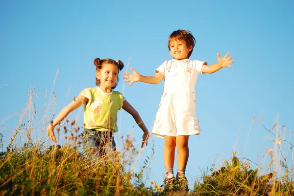 Menina e criança feliz pulando e gozando na natureza — Fotografia de Stock