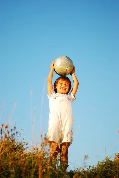 Piccolo ragazzo carino con palla sopra la testa in luogo adorabile all'aperto — Foto Stock