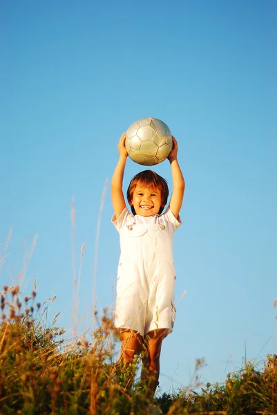 Kleine süße Junge mit Ball über dem Kopf in entzückenden Ort im Freien — Stockfoto