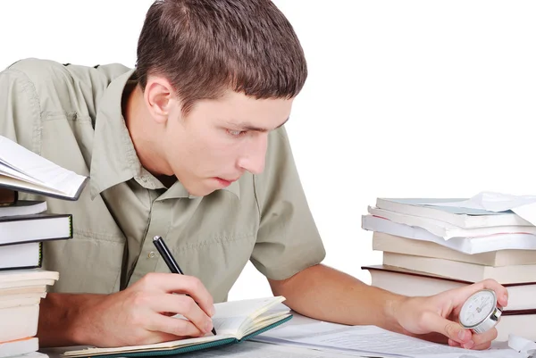 Молодой человек пишет на столе с книгами Лицензионные Стоковые Фото